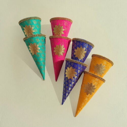 A vibrant collection of FS Jamawar Cones filled with traditional items for a desi wedding event. FS Jamawar Cones are the definitive solution for hosts and planners seeking to infuse their events with authentic royalty, vibrant colour, and functional beauty. They transform simple acts of gifting and decoration into profound cultural statements. Please Note: Due to the handcrafted nature of FS Jamawar Cones, all sales are final under our no refund, no exchange policy.